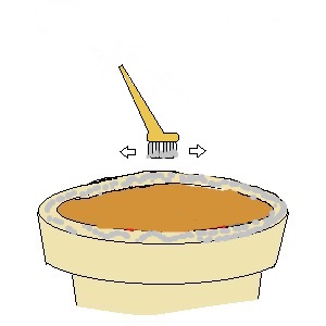 刷毛を使って七輪の油汚れを灰で落とす