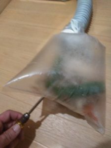 生ゴミを入れたビニール袋に穴をあけている様子